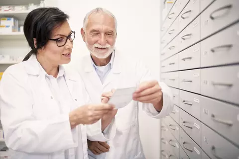 Lékárníci mluví a koukají na recept v lékárně