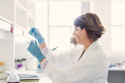 Vědkyně v laboratoři pracuje se zkumavkou