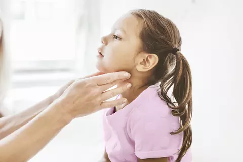 Doktorka vyšetřuje dítě, hmatá na uzliny na krku