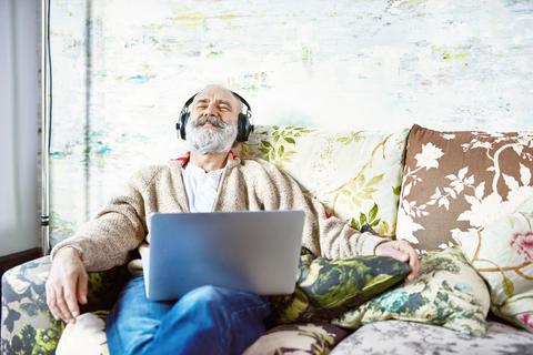 Muž na gauči spokojeně poslouchá hudbu